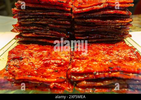 Grandi pezzi di kwa di bak grigliati al momento, salata carne di maiale dolce a fette sottili, qualità e quantità sul display della finestra. Singapore. Foto Stock