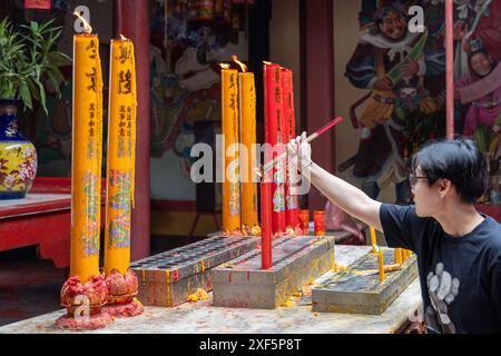 Bangkok, Thailandia. 24 giugno 2024. Una donna asiatica ha visto accendere i suoi bastoncini di incenso con una candela, all'interno del santuario Kian un Keng. Bangkok è un crogiolo di culture, religioni e costumi. Prevalentemente buddista, ha una storia di accoglienza dei coloni con credenze diverse. Bangkok ospita santuari, templi e chiese dove persone di varie fedi pregano per fortuna e fortuna. (Foto di Nathalie Jamois/SOPA Images/Sipa USA) credito: SIPA USA/Alamy Live News Foto Stock