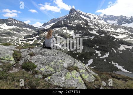 Una donna riposa su un altopiano roccioso nel Parco Nazionale degli alti Tauri di fronte a un imponente sfondo di montagna Foto Stock