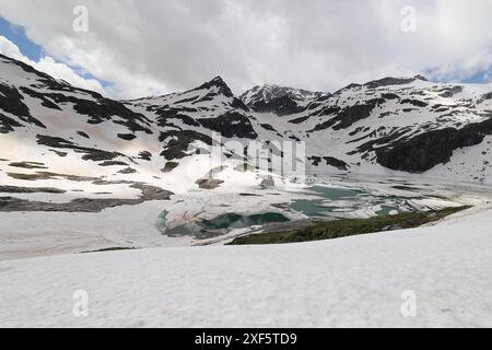 Vista del Weisssee verde smeraldo, parzialmente ancora congelato, di fronte alle imponenti vette delle montagne, del mondo glaciale degli alti Tauri, vista grandangolare Foto Stock