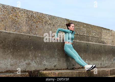 donna sportiva che fa un'esercitazione a spinta inversa, si allena all'esterno. Foto Stock