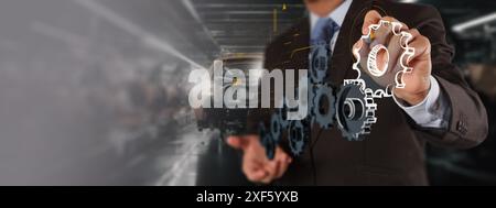 Un professionista in tuta interagisce con un'interfaccia digitale, mostrando le icone degli attrezzi e un'auto EV su una catena di montaggio. Questa immagine rappresenta l'uso di Foto Stock