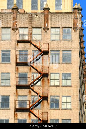 Una vecchia fuga antincendio si arrampica sul lato di un vecchio edificio nel centro di Memphis, Tennessee. Il metallo è diventato arancione rossastro con ruggine e scorre lungo il lato di bu Foto Stock