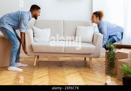 Allegro Afro coniugi posizionando il lettino Arredo camera vuota nella nuova casa Foto Stock