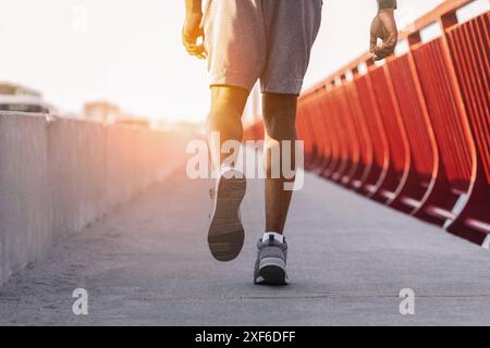 Immagine ritagliata di un uomo africano sportivo che corre sul ponte Foto Stock