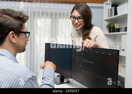 Sviluppatori esperti in team che pensano al più recente progetto software di pianificazione creativa del sito Web di codifica su due schermi pc, confrontandolo con la digitazione completa dello stack Foto Stock