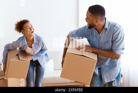 African American giovane che trasportano contenitori per il trasloco immettendo il nuovo appartamento Foto Stock