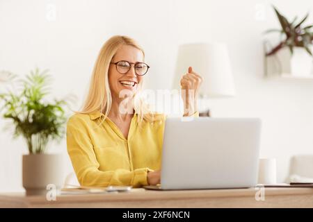 Raggiungere il successo. Donna matura la lettura di buone notizie su Laptop Foto Stock