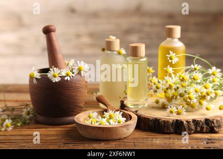 Diversi fiori e bottiglie di oli essenziali su tavola di legno Foto Stock