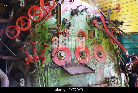 Una vecchia caldaia a vapore con comandi nella cabina di una locomotiva retrò abbandonata e non funzionante. Attrezzature da rubinetti, valvole, leve. Foto Stock