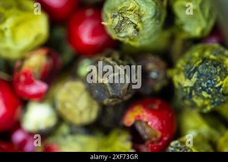 Primo piano macro un mix vibrante di grani verdi, rossi e neri di pepe Foto Stock