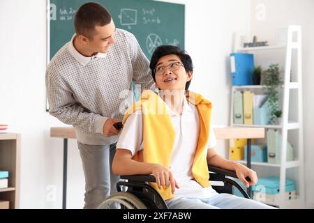 Adolescente con il suo compagno di classe in sedia a rotelle a scuola Foto Stock