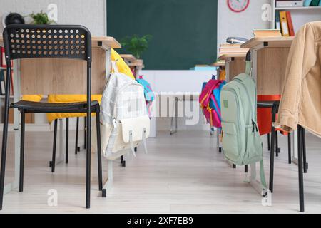 Scrivanie degli allievi con zaini in classe Foto Stock