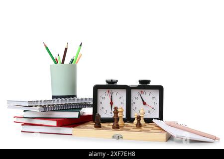 Composizione con cancelleria, scacchiera, pezzi e orologio su sfondo bianco Foto Stock