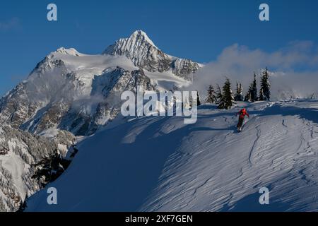 Stati Uniti, Stato di Washington. Sciatore sfidato dalla neve alla deriva del vento con il monte Shuksan sullo sfondo. (SIG.) Foto Stock