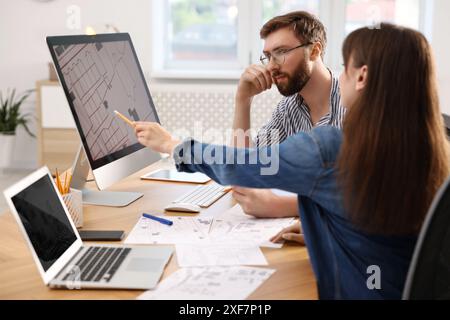 Cartografi che lavorano con la mappa catastale sul computer al tavolo in ufficio Foto Stock