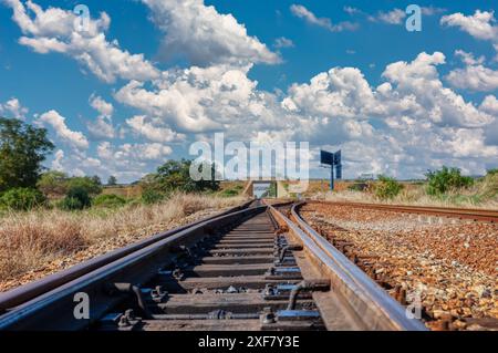 moderno attraversamento ferroviario su ghiaia che passa sotto il ponte, cielo blu diurno Foto Stock