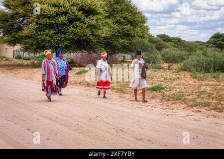 Donne africane Basarwa che camminano su una strada sterrata fuori dal villaggio, gente di San, nel Kalahari Foto Stock