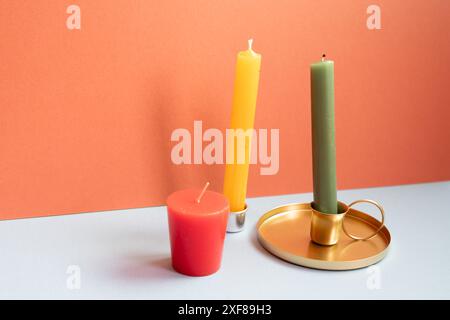 Candela sul tavolo grigio. sfondo rosso della parete Foto Stock