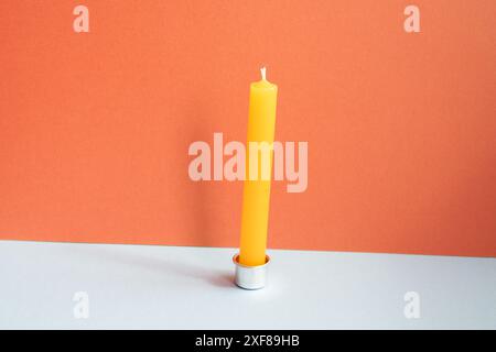 Candela sul tavolo grigio. sfondo rosso della parete Foto Stock