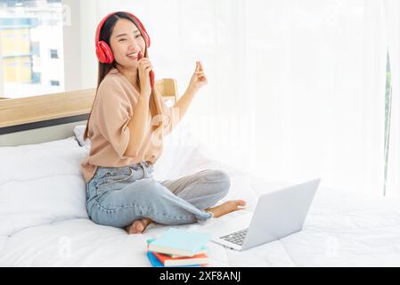 Rilassa la donna che tiene in mano un libro letto con le cuffie e ascolta la musica. Giovane donna relax leggendo un libro aperto mente per il tempo libero. Felicità bella donna pe Foto Stock