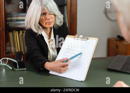 Donna professionista che spiega un documento durante una riunione - consulenza aziendale, consulenza, donna anziana in carica, discussione dettagliata, prof Foto Stock