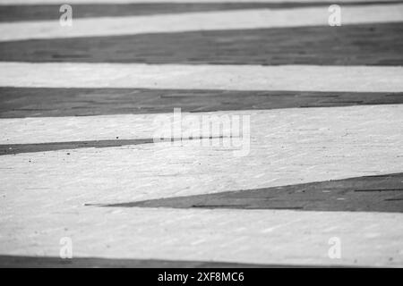 Foto di sfondo del marciapiede dell'area pedonale urbana, motivo di piastrelle in pietra grigia e bianca Foto Stock