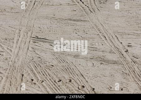 Vista dettagliata delle tracce degli pneumatici impresse su una superficie sabbiosa. L'immagine evidenzia gli intricati motivi e trame creati dagli pneumatici, rendendola identificabile Foto Stock