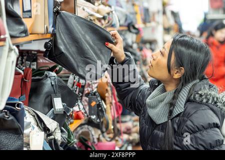 Una giovane donna sceglie una borsa in un negozio Foto Stock