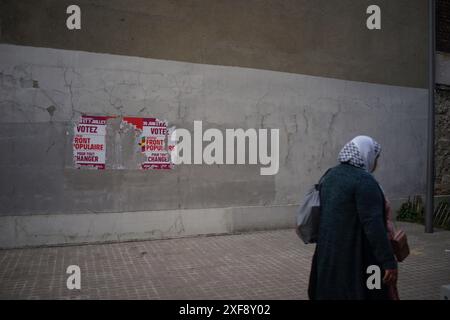 Una donna cammina davanti a un manifesto del fronte Popolare lacerato dopo la sconfitta elettorale del 30 giugno del fronte Popolare, 75019, Parigi, Francia credito: Jane Burke/Alamy Live News Foto Stock