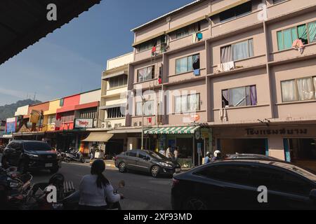 Città vecchia di Phuket con appartamenti residenziali con vestiti che si asciugano fuori dalle finestre città vecchia con moto e auto sulla strada trafficata. Negozi e ristoranti Foto Stock