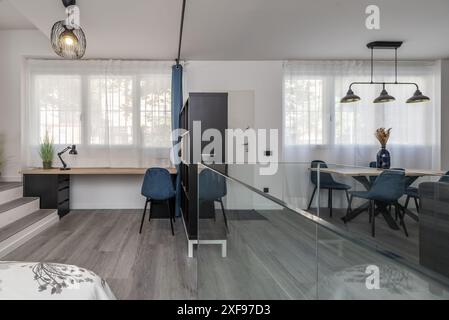 Caratterizzato da elementi come tavoli in pietra, sedie in metallo e lampade a vista, questo stile conferisce un tocco urbano e industriale al soggiorno Foto Stock