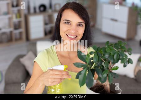 Donna felice spruzza acqua su albero di bonsai Foto Stock