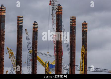 Diverse gru e pali in un cantiere in una giornata nuvolosa, rotterdam, paesi bassi Foto Stock