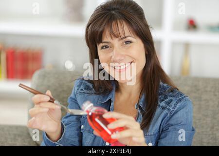 donna che versa farmaci o sciroppo antipiretico dal flacone al cucchiaio Foto Stock