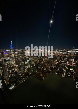 Vista notturna di una città con grattacieli e edifici illuminati sotto un cielo buio, New York, Stati Uniti Foto Stock