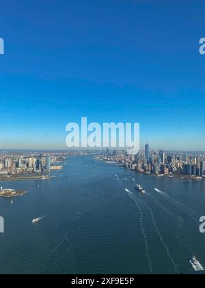 Vista aerea di un ampio corso d'acqua con navi e dello skyline di New York sullo sfondo in una giornata limpida con acque blu profonde, New York, Stati Uniti Foto Stock