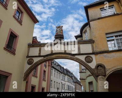 Un arco collega due edifici in una città vecchia, coronati da una scultura e decorati con antichi rilievi, treviri, germania Foto Stock