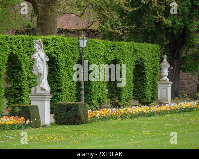 Un giardino ben tenuto con siepi, aiuole di fiori e statue lungo un sentiero, treviri, germania Foto Stock
