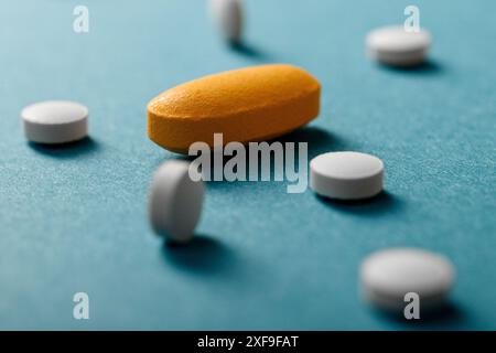 Primo piano di pillole bianche e gialle su sfondo blu Foto Stock