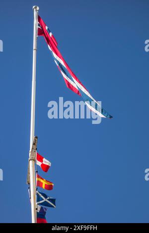 Bandiere norvegesi e altre bandiere che volano su un palo di fronte a un cielo azzurro, haugesund, norvegia Foto Stock