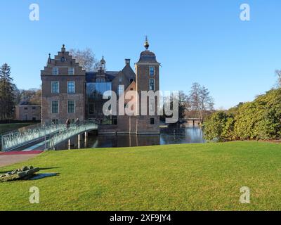 Un castello storico con un moderno ponte di vetro su un corpo d'acqua in un paesaggio verde ben curato in una giornata di sole, Ruurlo, gheldria, paesi bassi Foto Stock