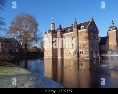 Uno storico castello in mattoni vicino all'acqua, circondato da erba e alberi, in una giornata di sole, Ruurlo, gheldria, paesi bassi Foto Stock