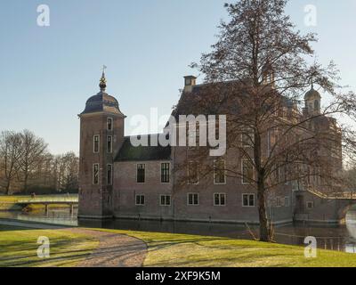 Uno storico castello in mattoni con torrette vicino all'acqua, circondato da un sentiero, alberi e prato, ruurlo, gheldria, paesi bassi Foto Stock