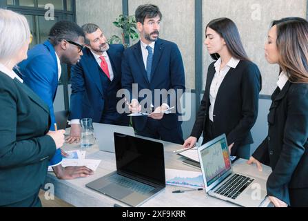 Uomini d'affari che discutono di un progetto in un ufficio. Lavoro di squadra e collaborazione in un ambiente di lavoro creativo. Foto Stock