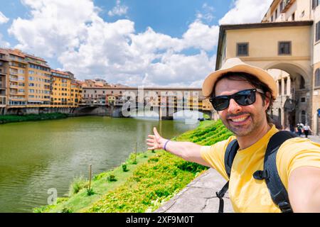 Giovane che scatta un selfie di fronte al Ponte Vecchio a Firenze, in Toscana, durante le sue vacanze estive in Europa. Foto Stock