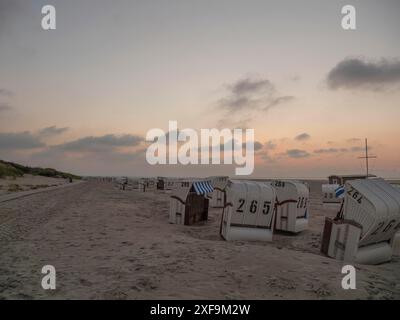 Sedie a sdraio al tramonto sulla spiaggia sotto un cielo nuvoloso, Spiekeroog, mare del nord, germania Foto Stock