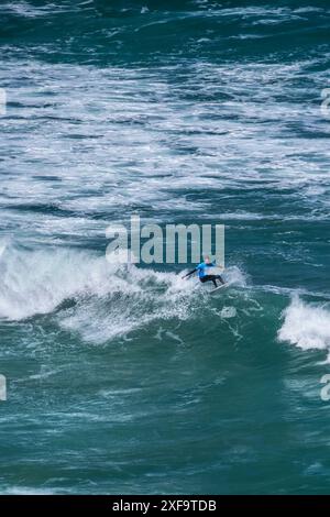 Un surfista che cavalca un'onda al largo della costa di Newquay in Cornovaglia nel Regno Unito. Foto Stock