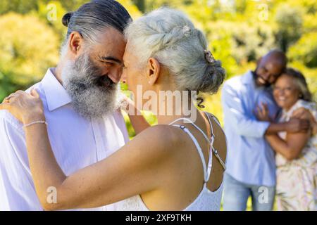 Abbracciante e sorridente, sposa senior e sposo al matrimonio all'aperto per divertirsi insieme Foto Stock
