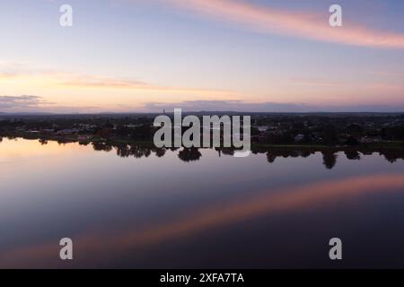 Una serena scena serale a Grafton, New South Wales, Australia. Il cielo è dipinto con sfumature di arancione e rosa mentre il sole tramonta sulla tranquilla Clare Foto Stock